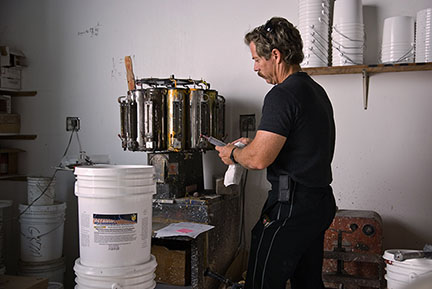 Owner tinting custom color roof coating in 5-gallon pails at The Roof Store factory in Davie Florida